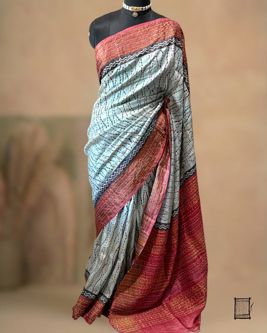 The body of this sophisticated grey saree features unique wavy Kantha lines that mimic the flow of water.