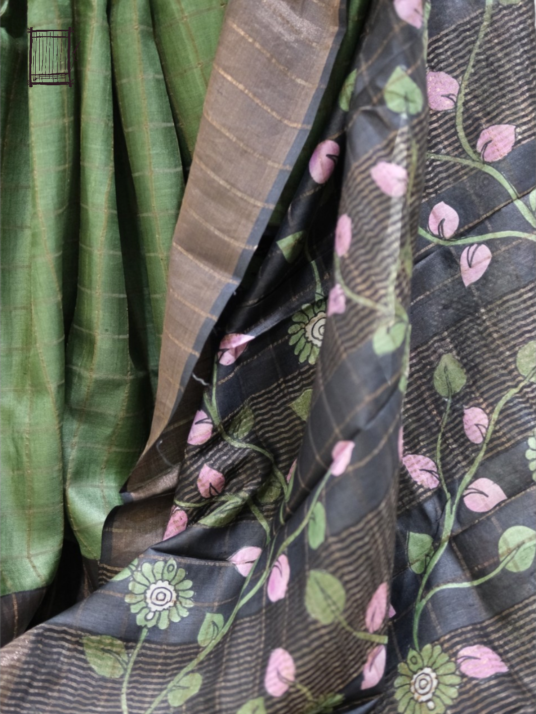 Pleats and pallu — forest green pleats falling beside charcoal kalamkari with pink leaf motifs