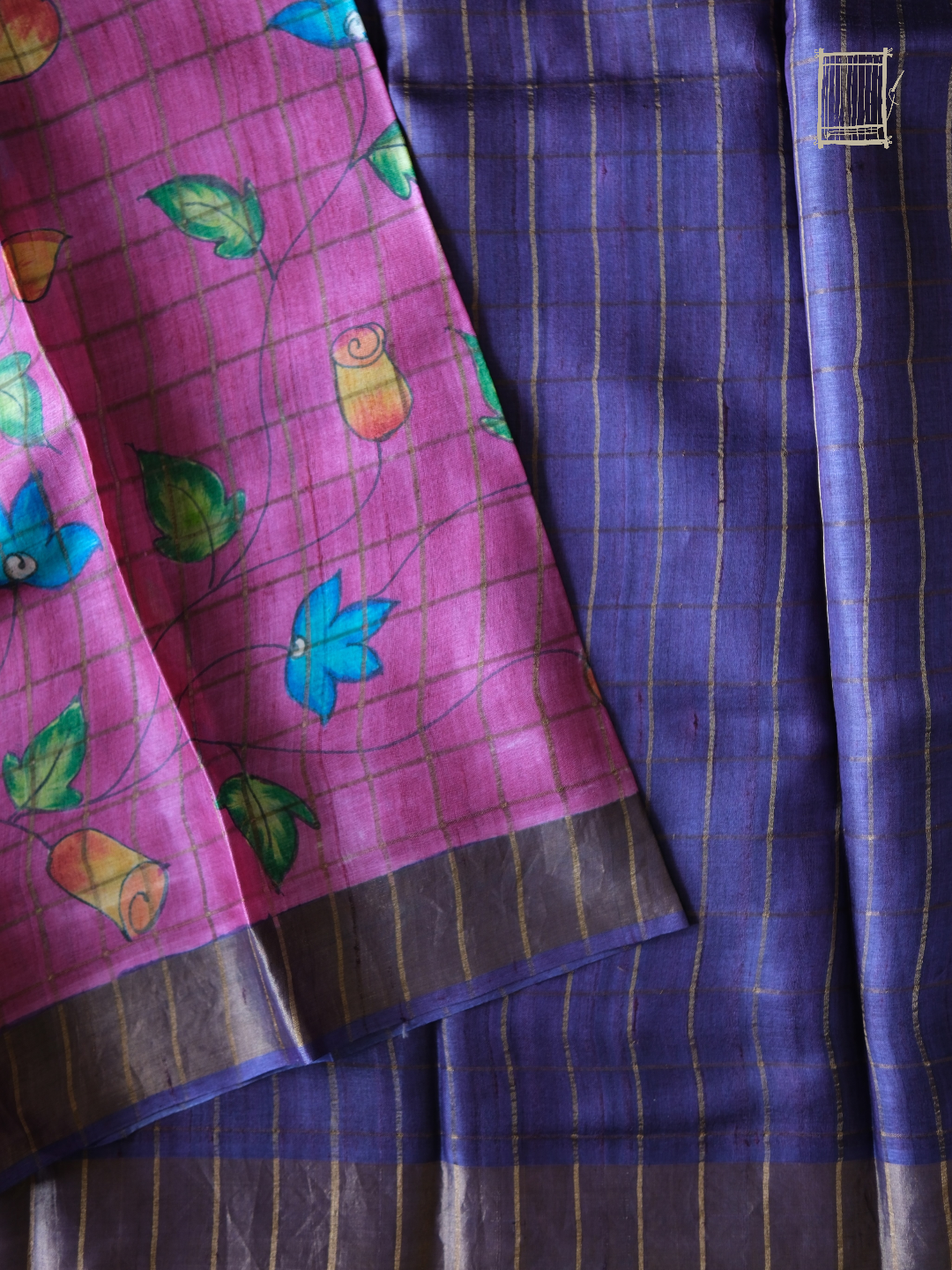 Navy violet check blouse piece folded over magenta kalamkari pallu with floral motifs