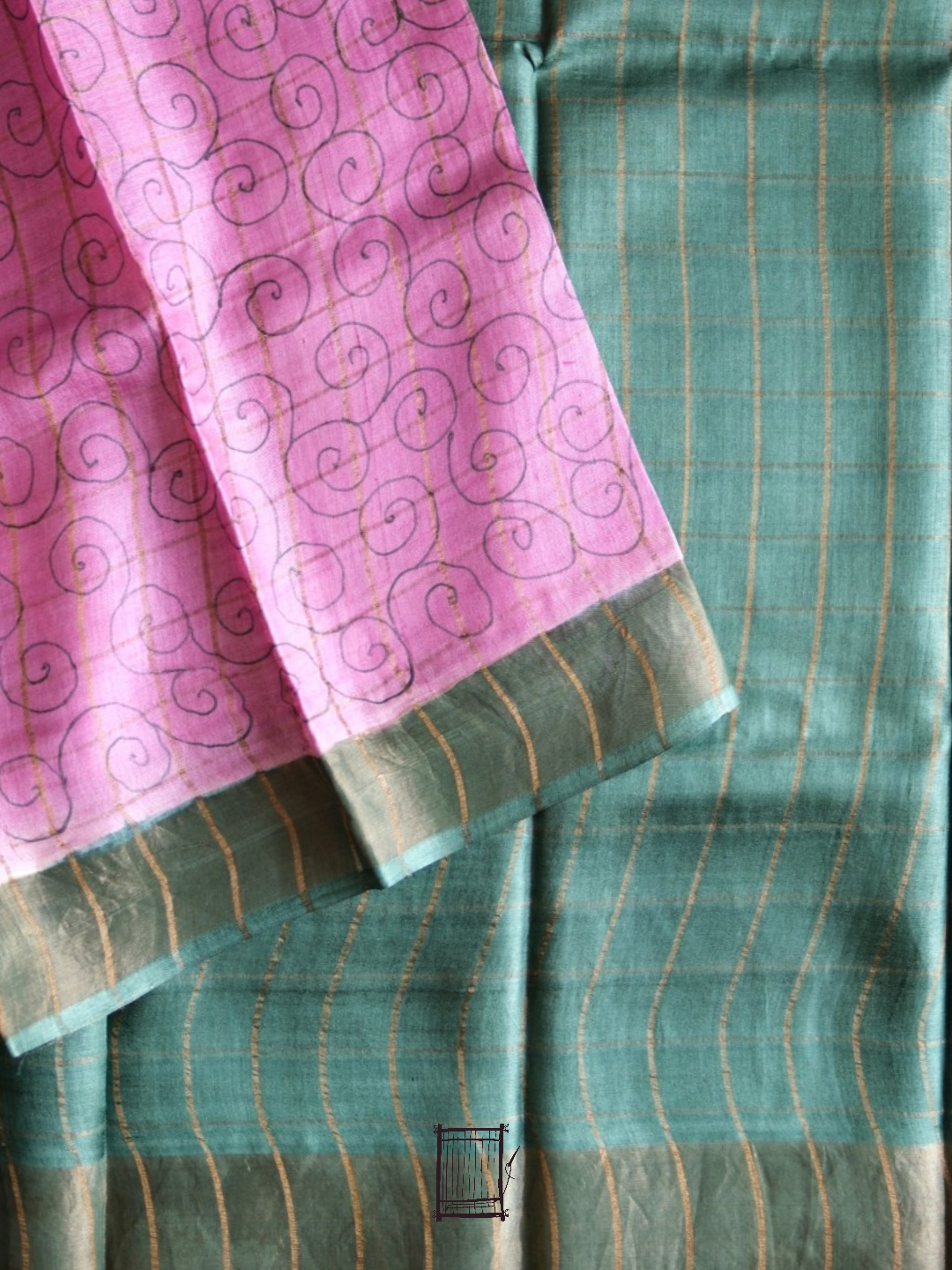 Pink swirl-motif blouse piece folded over teal tussar saree body with gold zari checks
