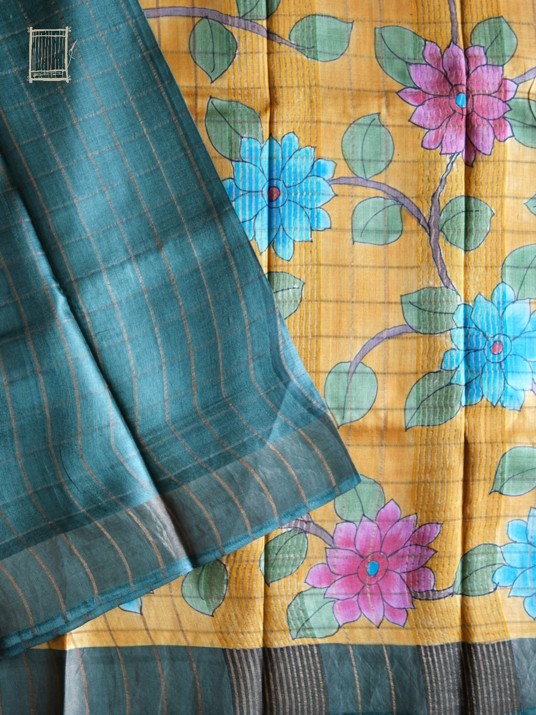 Close-up of mustard kalamkari pallu with pink lotuses and turquoise florals against teal tussar body